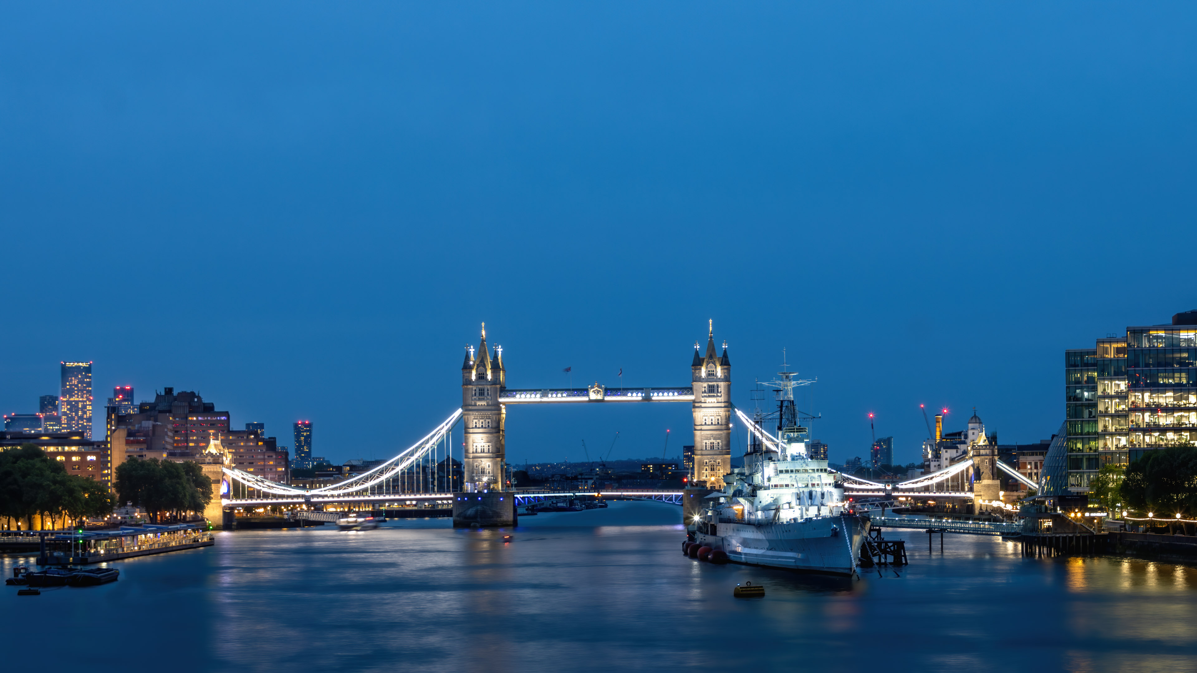Experience the beauty of London's Tower Bridge at night with this high-quality wallpaper. Perfect for anyone who loves the city life.