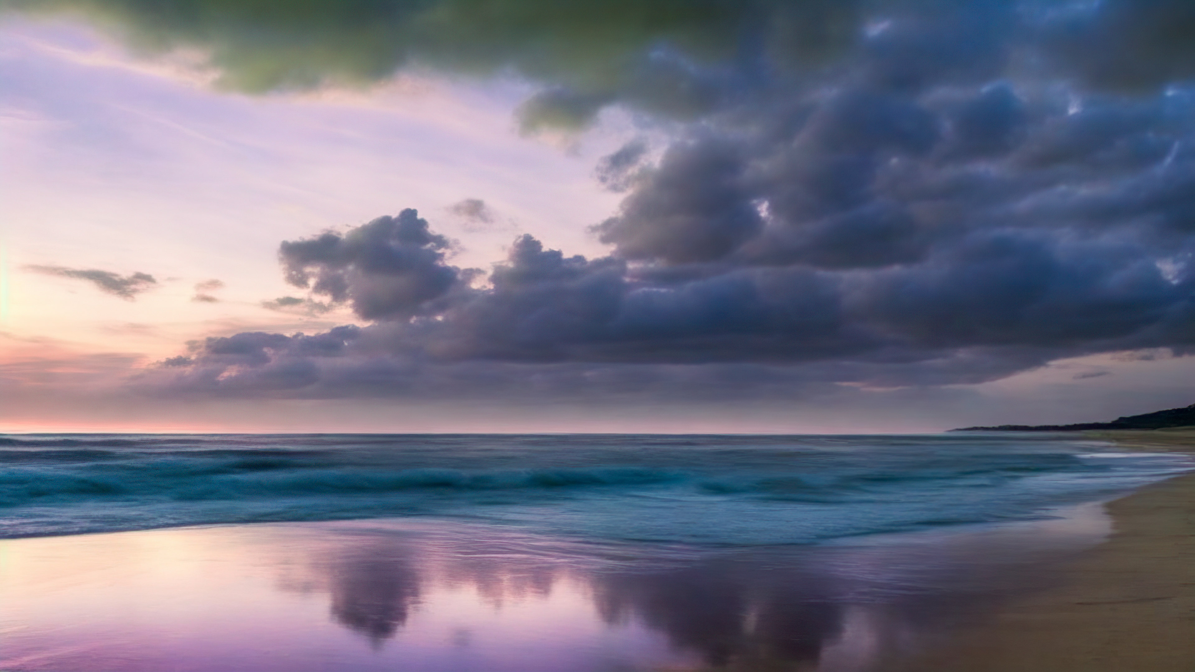 Perdez-vous dans la magie de notre fond d'écran en HD des paysages dépeignant une plage tranquille au crépuscule, avec le ciel peint en nuances de violet et de rose, et laissez votre écran vous transporter vers un lieu de paix et de sérénité.