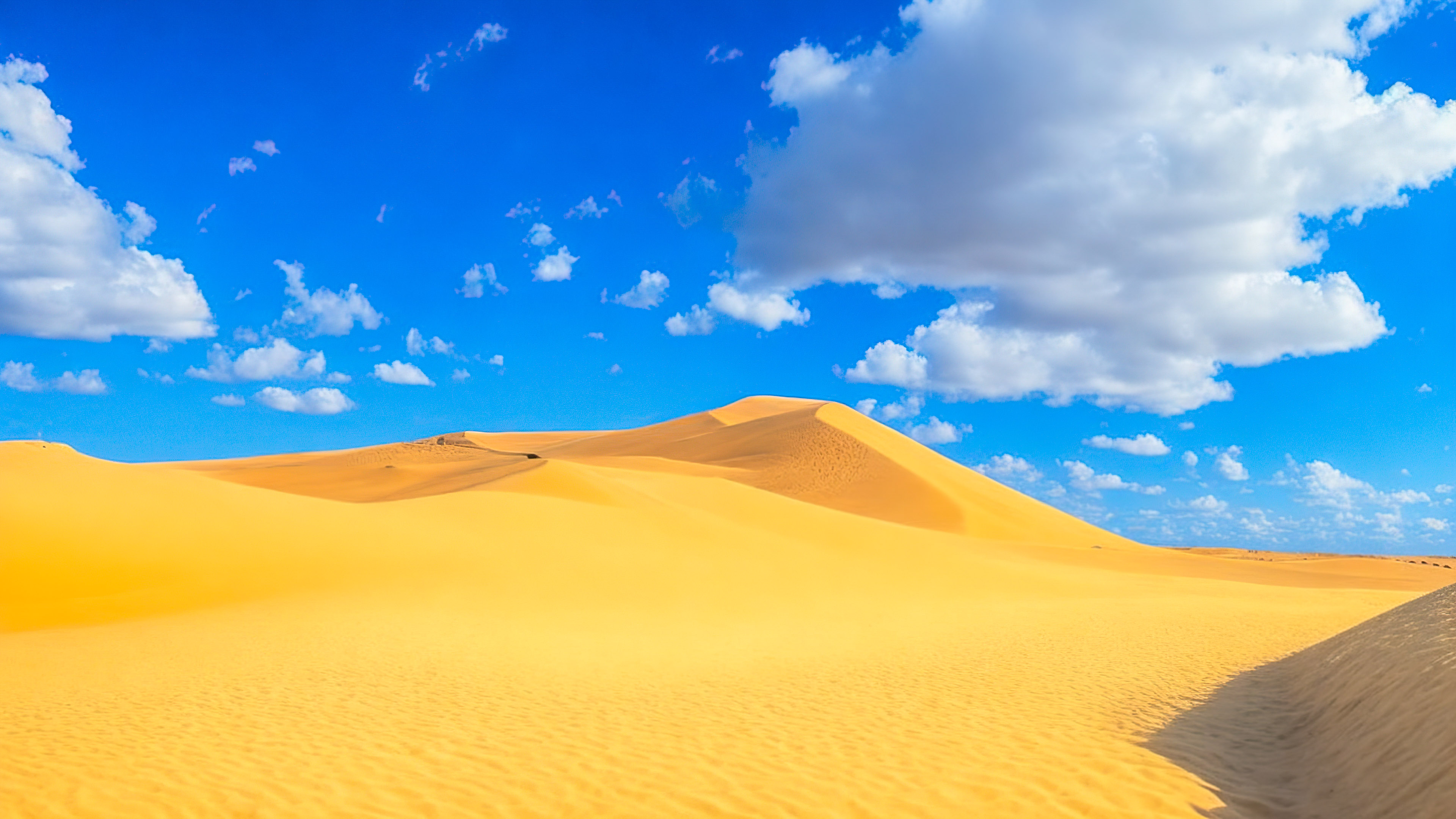 Perdez-vous dans la magie de notre joli fond d'écran de ciel, dépeignant un paysage désertique serein avec des dunes de sable s'étendant jusqu'à l'horizon sous un vaste ciel bleu, et laissez la beauté vous captiver.