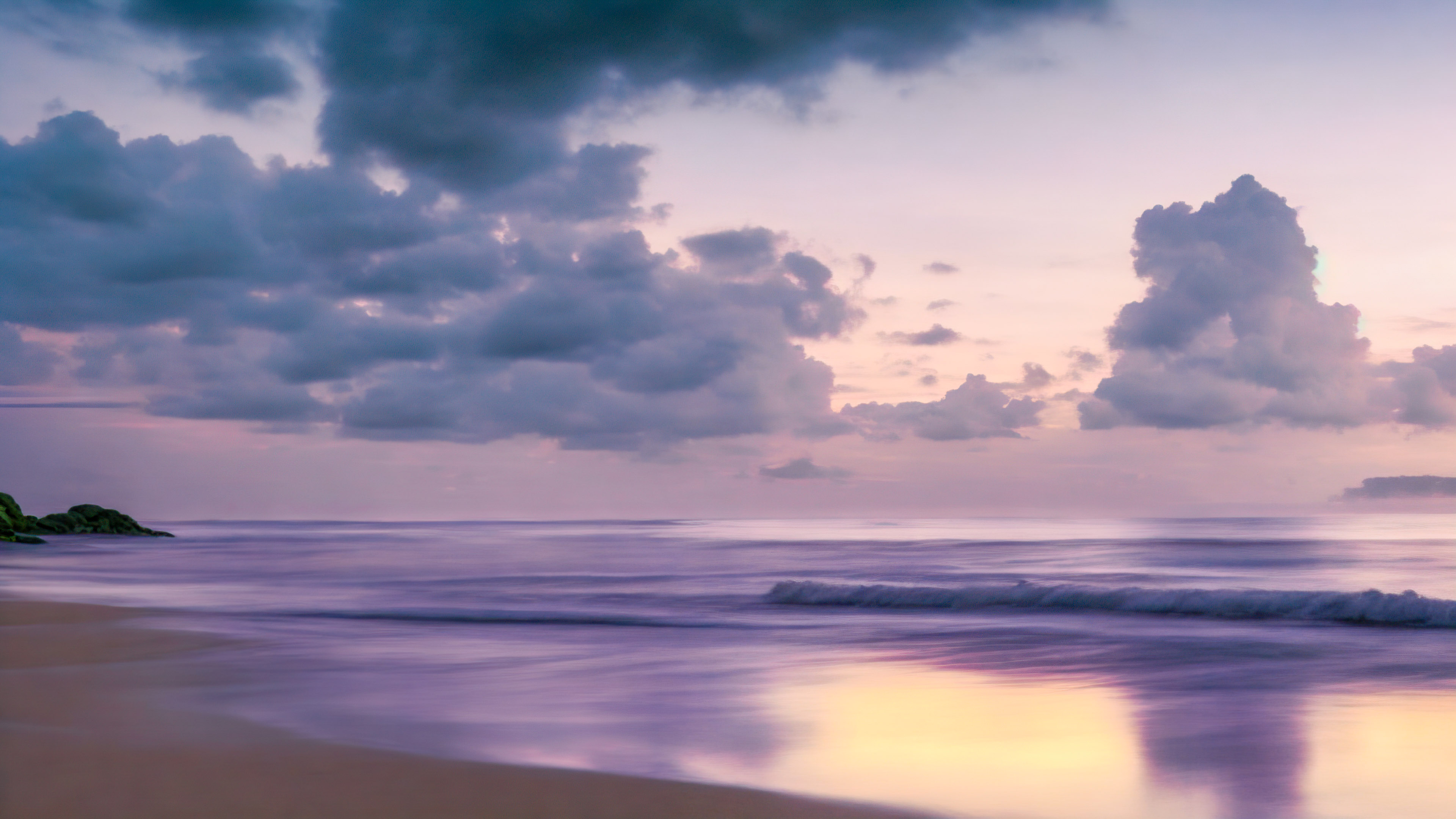 Transform your device’s screen with sky background in 4K, showcasing a tranquil beach at twilight, with the sky painted in shades of purple and pink.