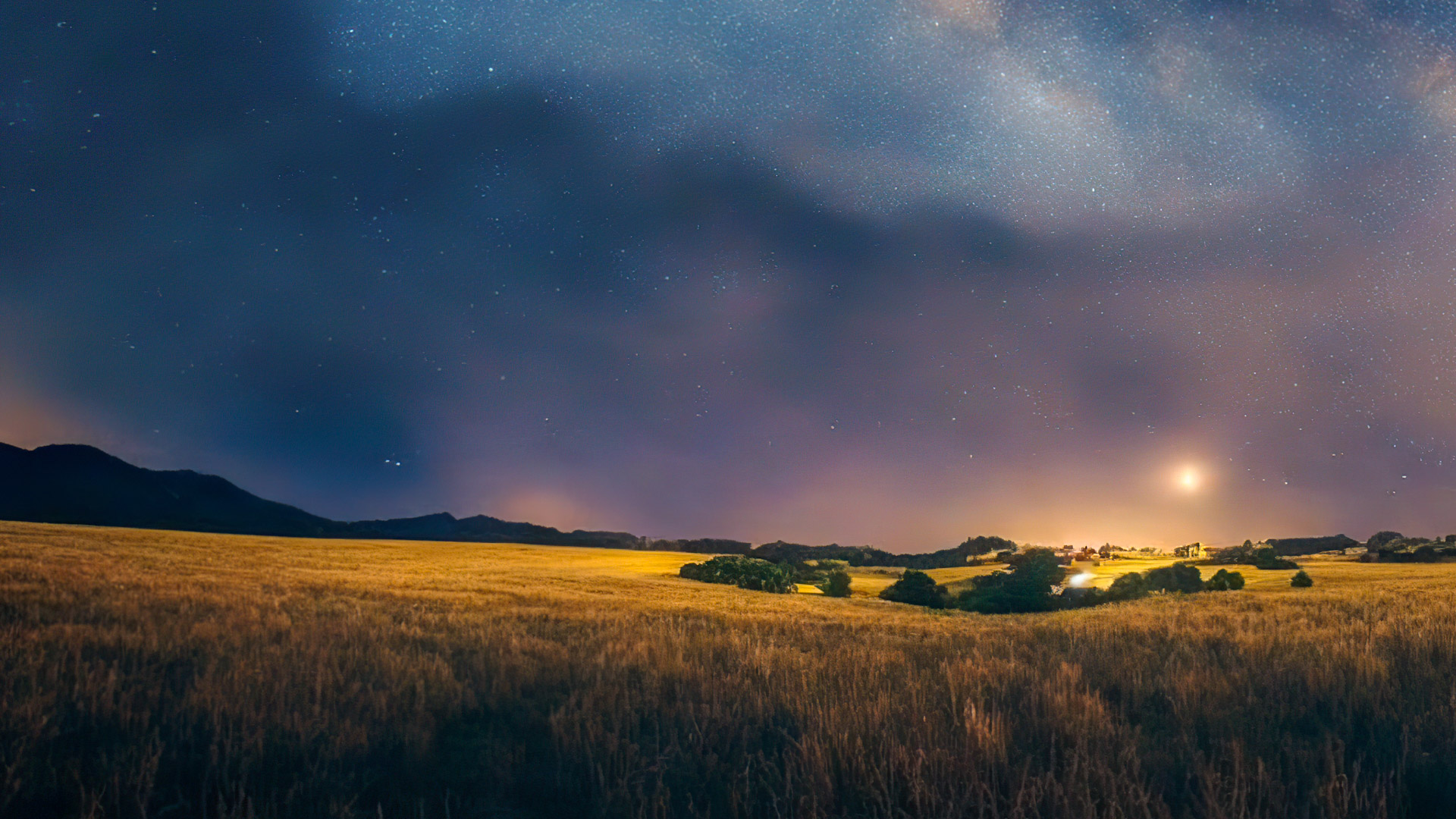Téléchargez des fonds d'écran d'arrière-plan de nature en HD 1080p, illustrant un ciel nocturne clair et étoilé à la campagne, avec la Voie lactée s'étirant à l'horizon.