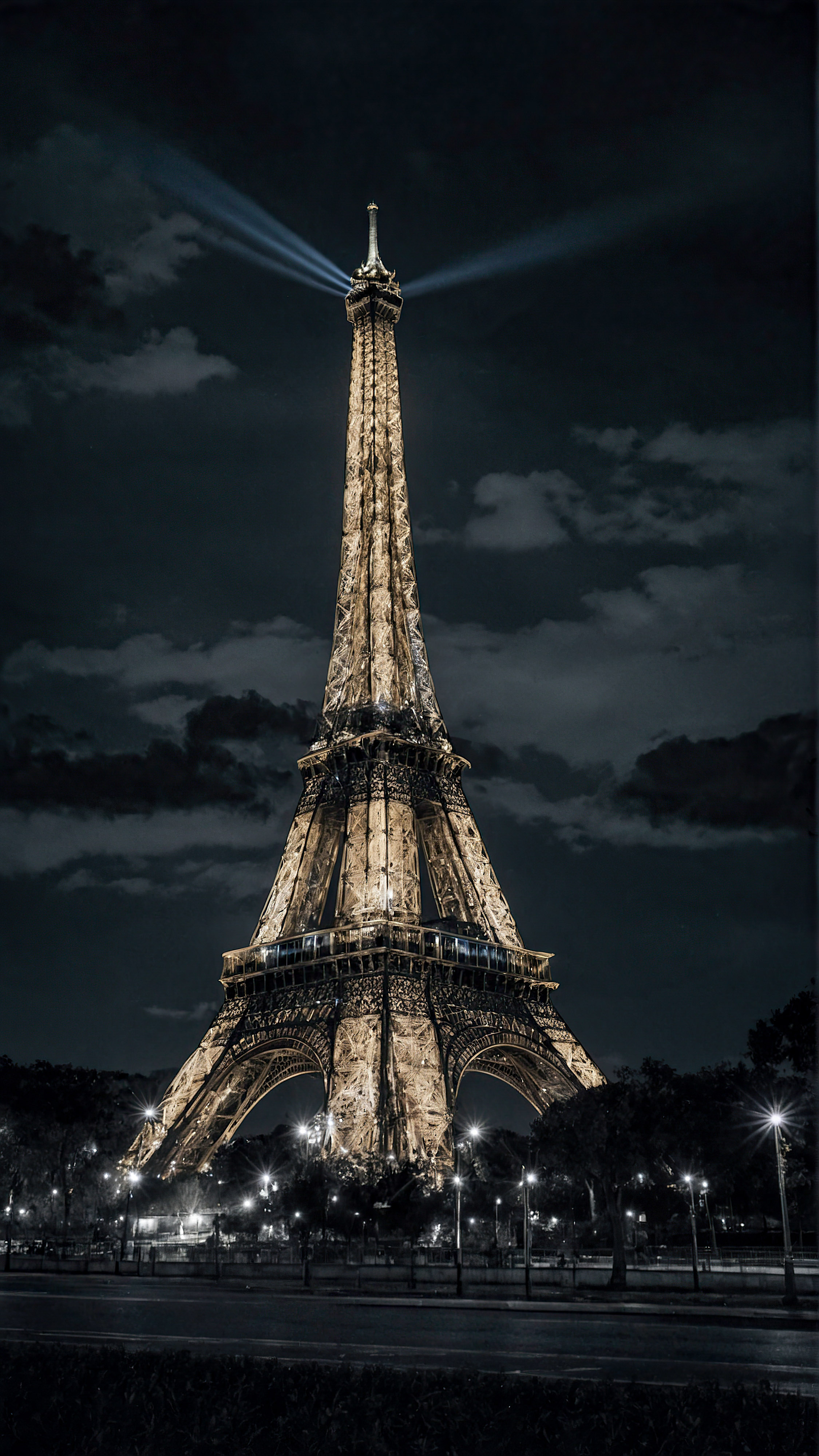 Vivez le charme de Paris avec notre fond d'écran iPhone noir en 4K, présentant la Tour Eiffel illuminée la nuit, se dressant majestueusement contre un ciel sombre. 