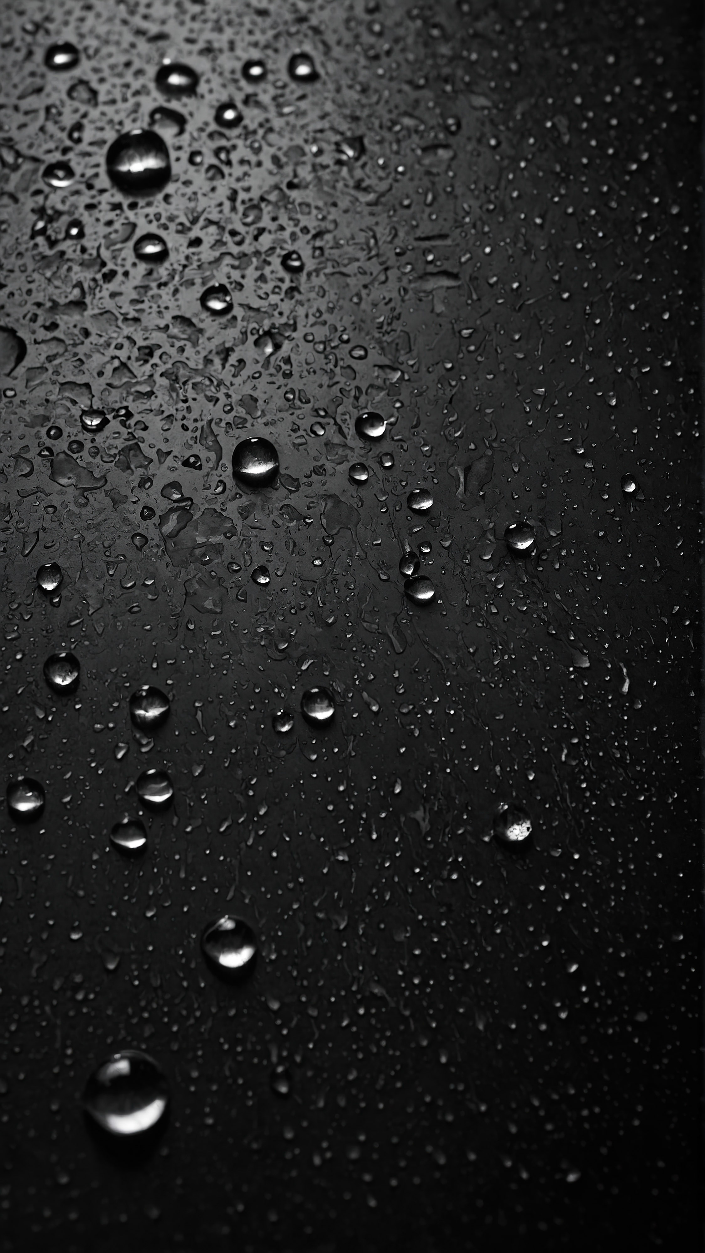 Ressentez la texture des gouttes d'eau sur une surface sombre, capturée dans notre arrière-plan noir pour iPhone en 4K gratuit. 