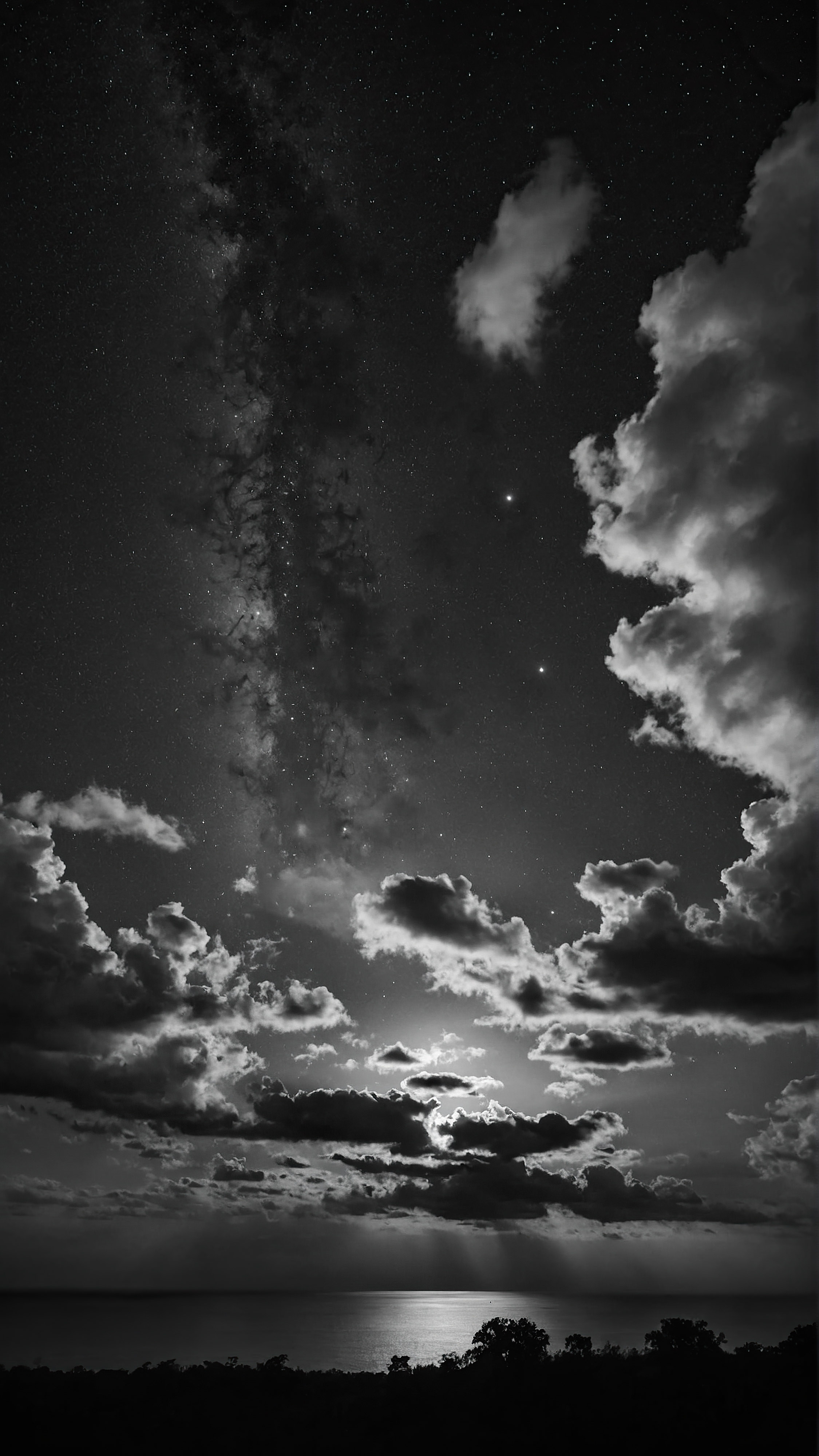 Experience the depth of a night sky, adorned with dense clouds and visible stars, through a 4K black iPhone wallpaper.