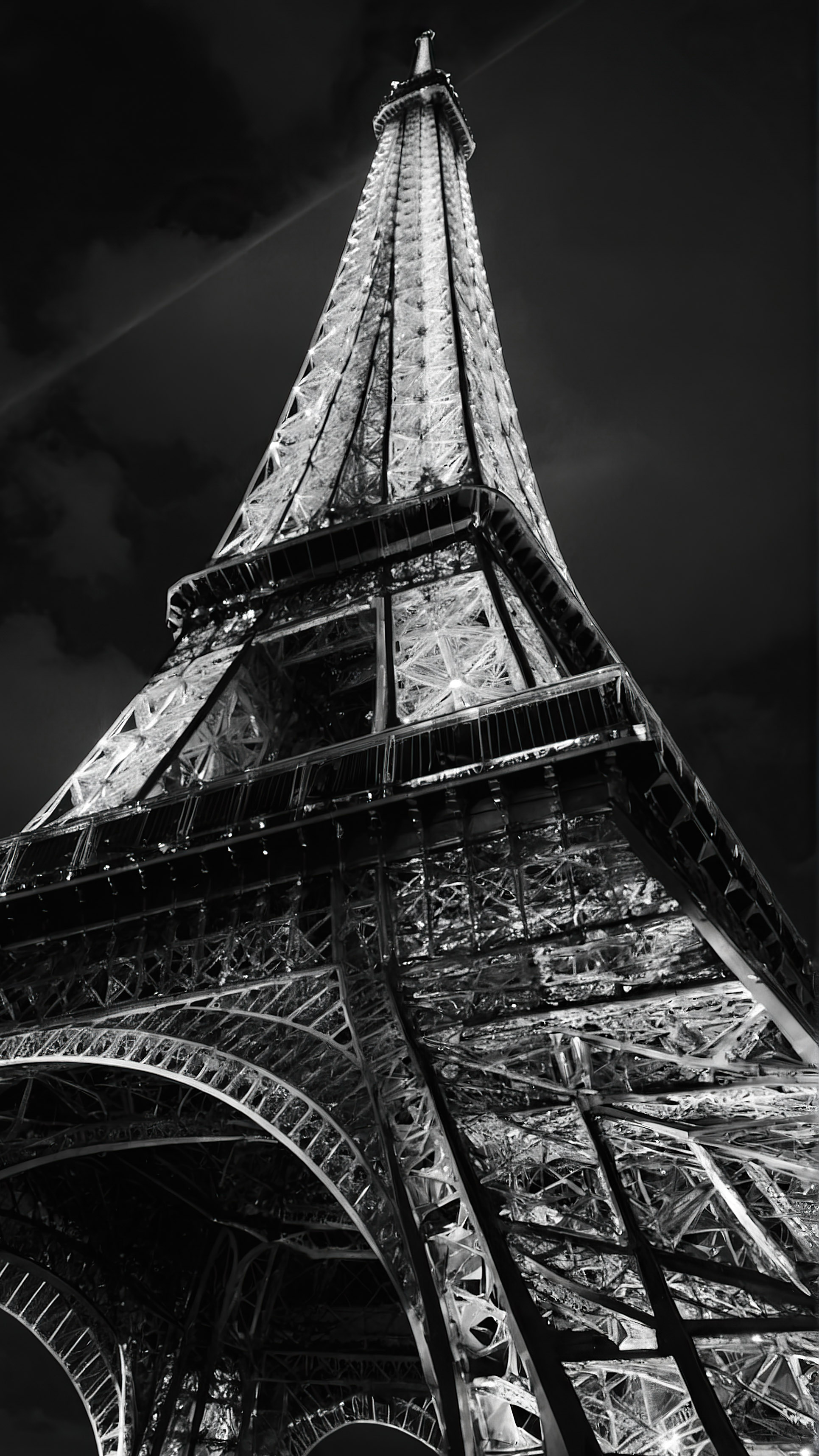 Découvrez l'élégance de notre fond d'écran noir pour iPhone en 4K, mettant en vedette la Tour Eiffel, se dressant fièrement et brillamment éclairée contre un ciel noir. 