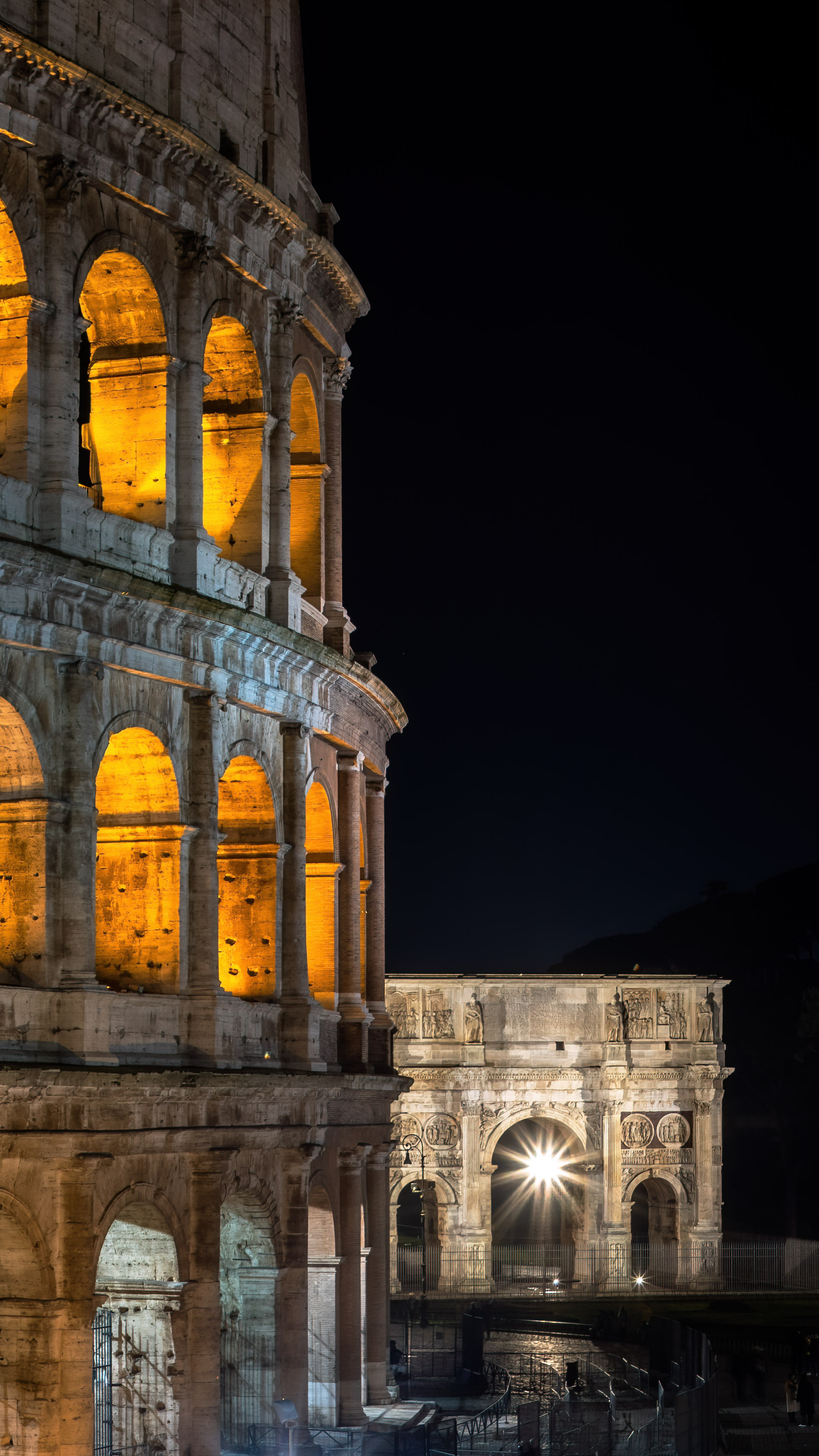 Get wallpaper of charming Colosseum in Rome city at night with colorful lights and buildings