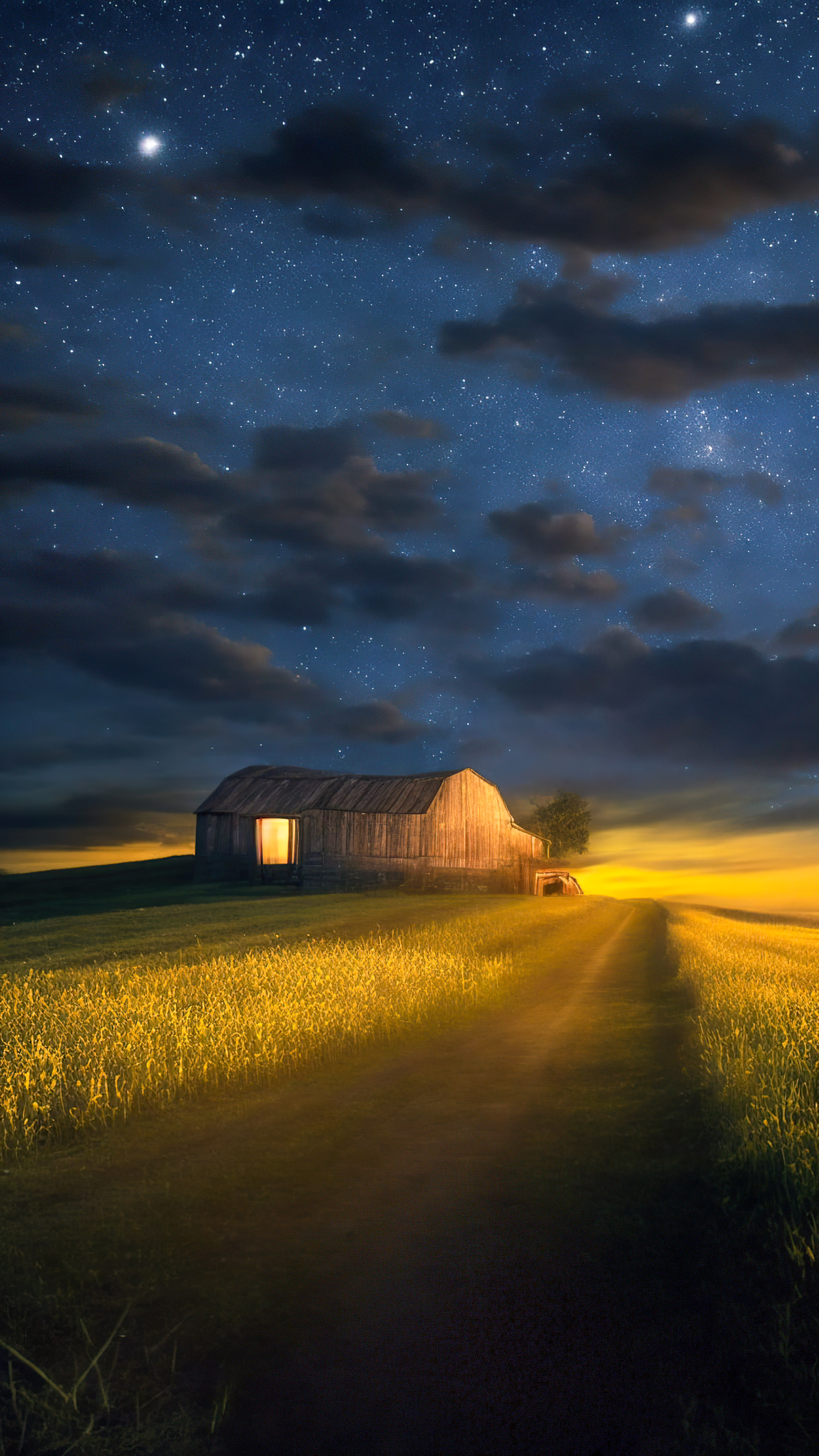 Le meilleur fond d'écran de nature en 4K pour votre mobile vous attend, présentant une scène de campagne sereine, une grange rustique, des lucioles et un ciel étoilé et clair.