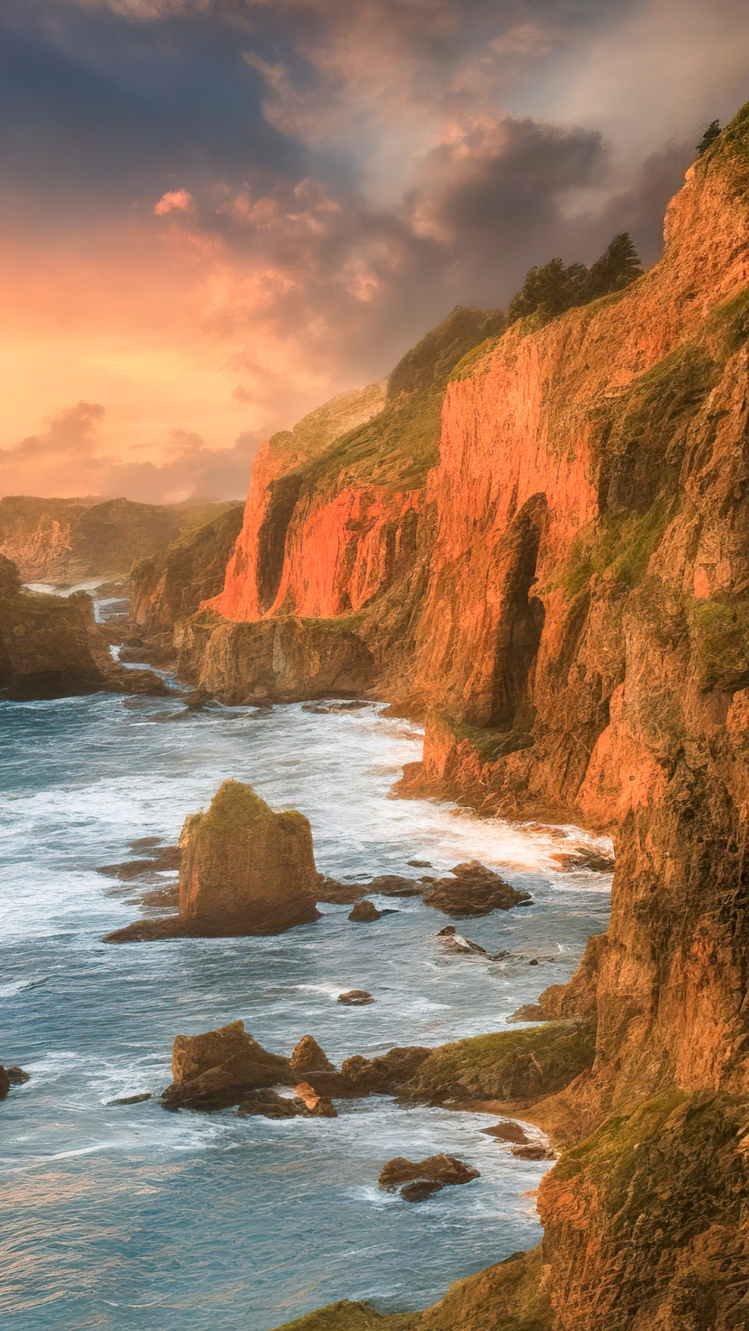 Téléchargez notre fond d'écran de nature pour Android en HD 1080p, présentant une vue côtière époustouflante avec des falaises rugueuses, des vagues déferlantes et un coucher de soleil enflammé.