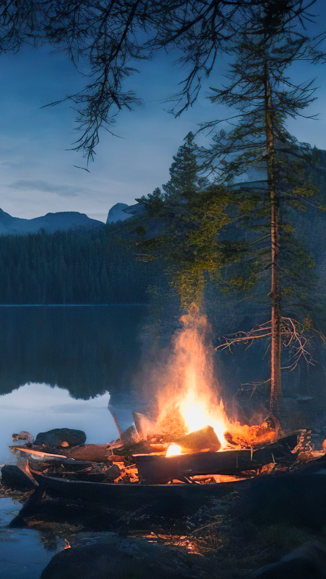 Ornez votre iPhone avec notre fond d'écran de paysage de haute qualité, mettant en scène un campement paisible au bord d'un lac avec un feu de camp vacillant, entouré d'une forêt sauvage sombre.